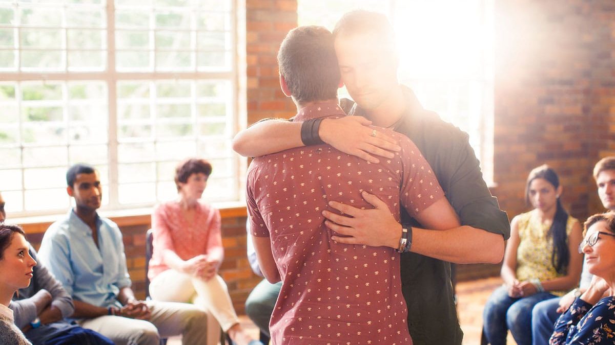 People at an addiction treatment program in Massachusetts hugging during group therapy