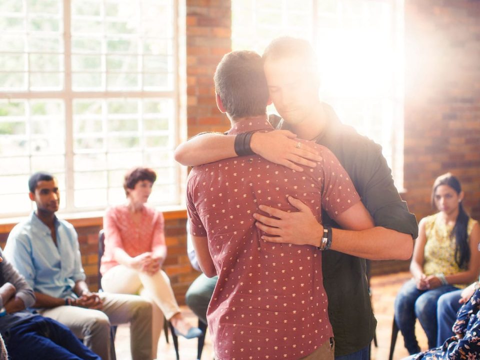 People at an addiction treatment program in Massachusetts hugging during group therapy