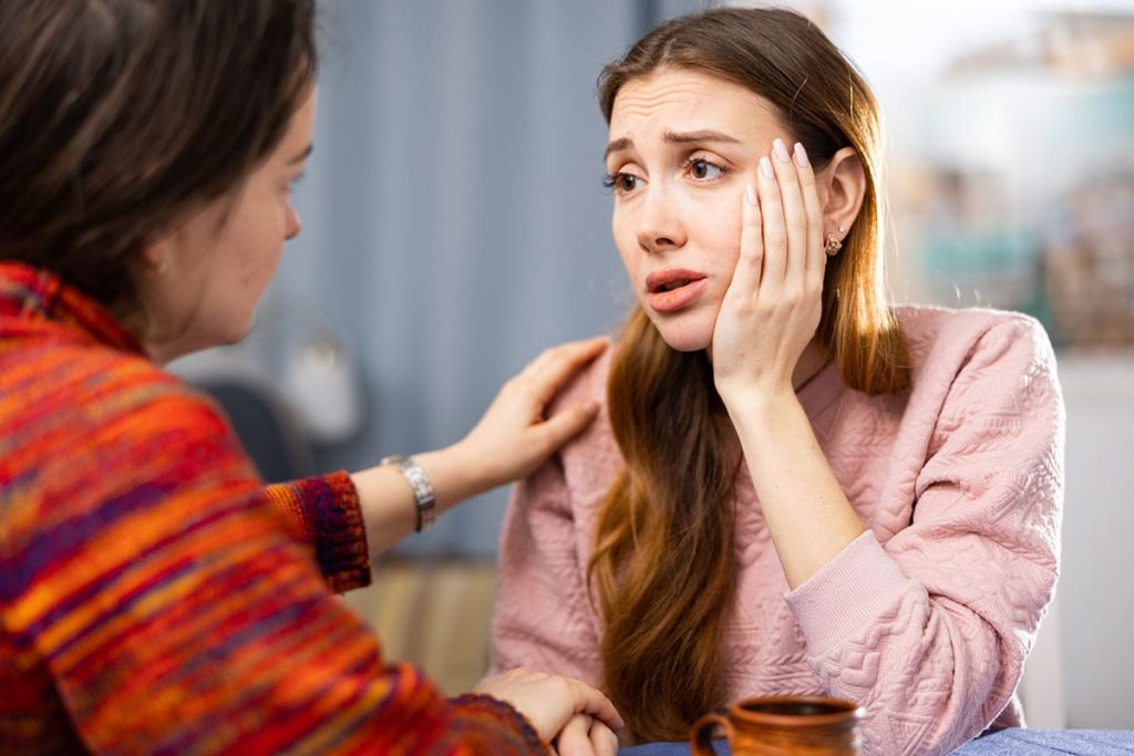 Concerned mother with hand up to face, asking friend "is my loved one addicted to drugs?"