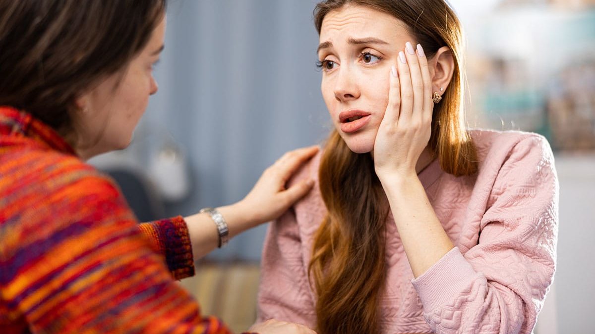 Concerned mother with hand up to face, asking friend "is my loved one addicted to drugs?"