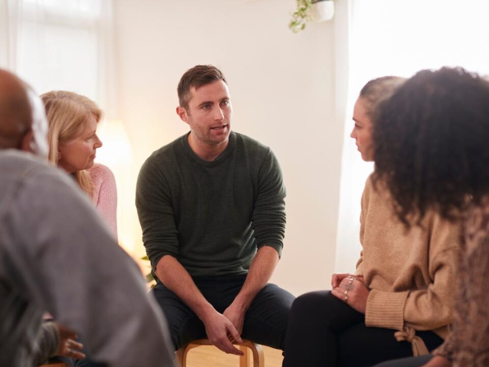 Man talks to peers in group therapy after learning what an outpatient program is all about