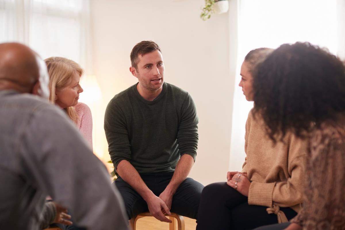 Man talks to peers in group therapy after learning what an outpatient program is all about