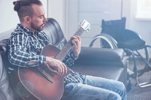 Man sits on couch playing guitar in music therapy program