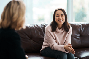 Woman sits on couch and smiles during relapse prevention therapy